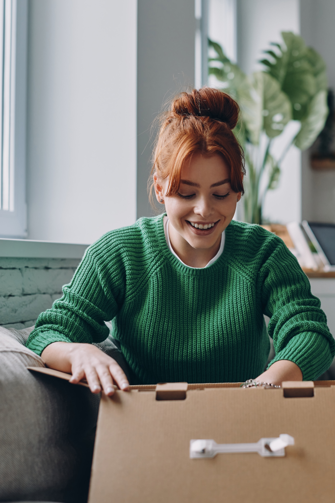 Smiling woman eagerly unboxing a package on her couch.