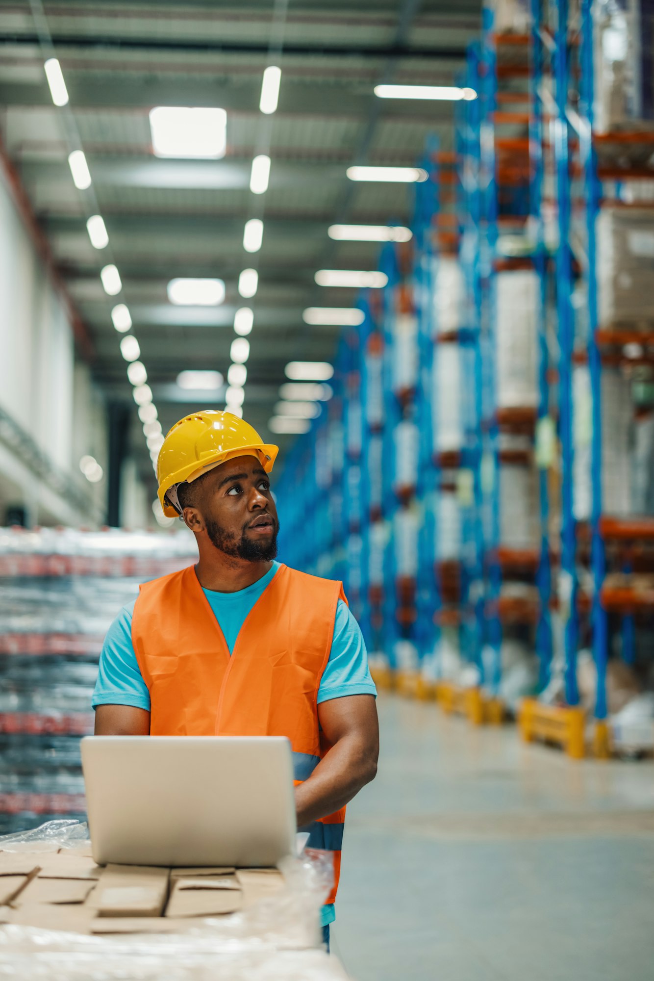 Warehouse employee updating inventory with a laptop.