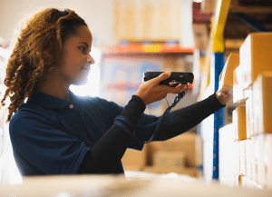 Warehouse employee scanning boxes with a handheld device to track inventory accuracy.